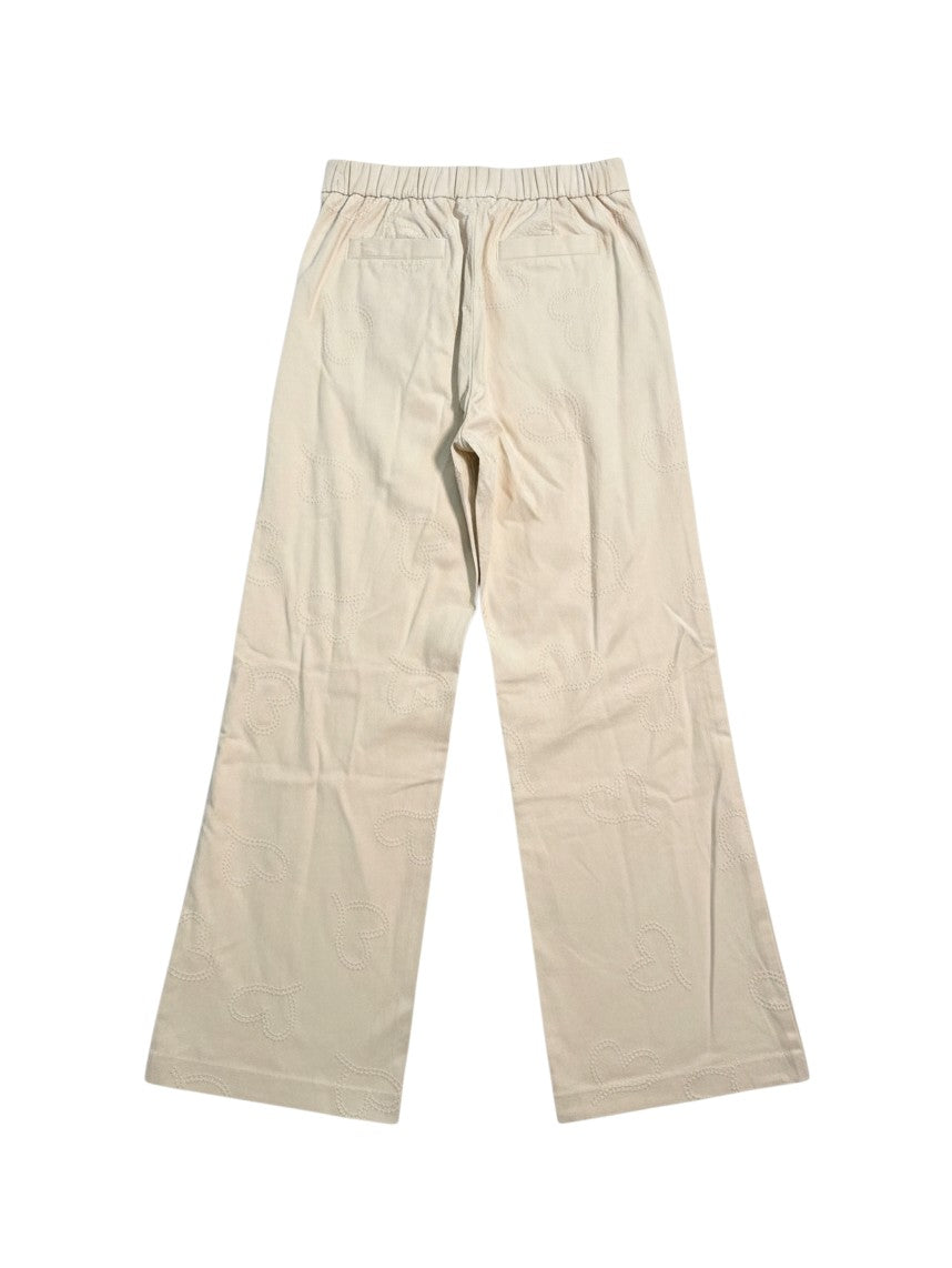 Yanet Collection Shop beige wide-leg trousers featuring an all-over embossed heart pattern and elasticated waistband.