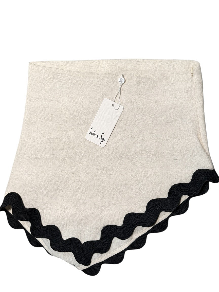 Yanet Collection Shop beige linen skirt featuring a black wavy scalloped hem and a Sadie & Sage brand tag.