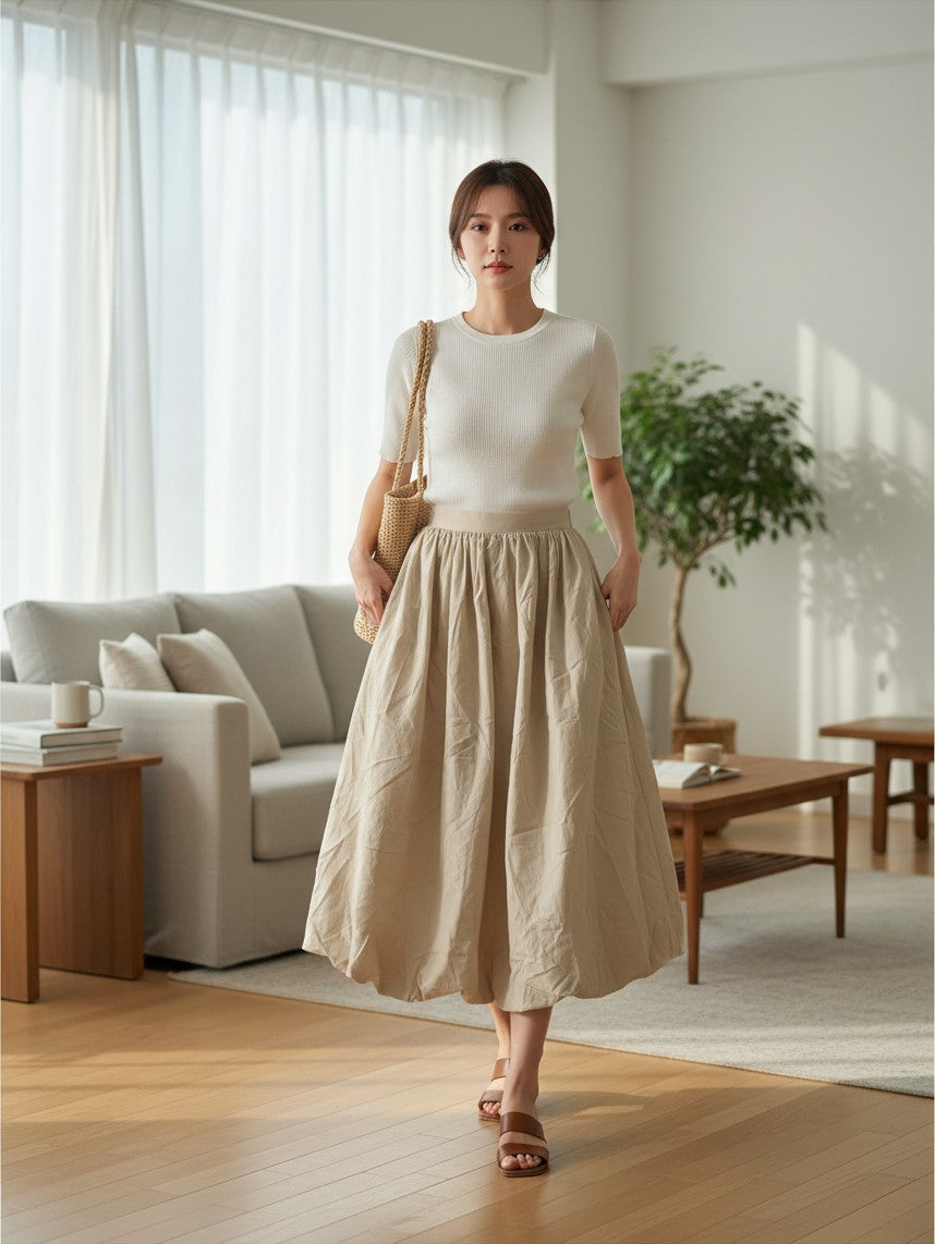 Yanet Collection Shop model wearing a white ribbed knit top and a beige midi skirt with a woven straw bag