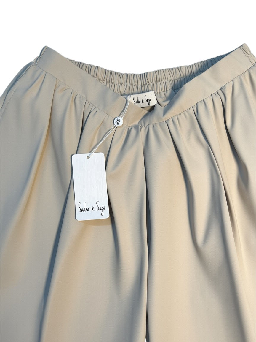 Yanet Collection Shop beige high-waisted pleated trousers with an elastic waistband and Sadie & Sage brand tag