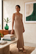 Yanet Collection Shop beige sleeveless ribbed maxi dress with button detail worn by a woman in a modern living room