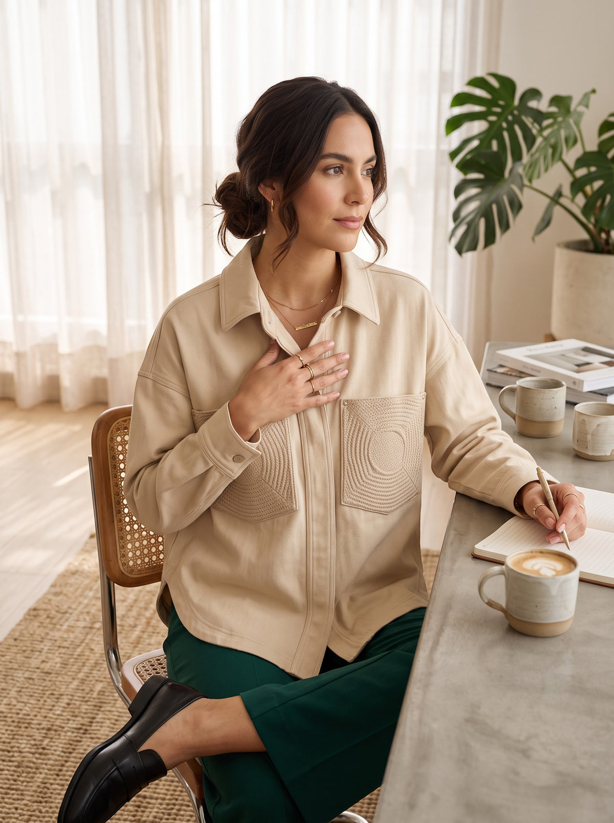 Woman wearing a beige Yanet Collection Shop jacket with textured pocket details while sitting at a desk.