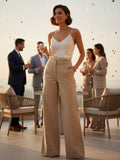 Yanet Collection Shop woman in a cream silk camisole and beige wide-leg trousers with heart embroidery at a party.