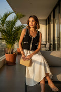 Yanet Collection Shop black cropped knit vest with striped trim and button front worn by a woman on a balcony