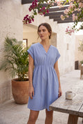 Yanet Collection Shop blue striped short sleeve dress with a v-neckline and waist tie worn by a woman outdoors