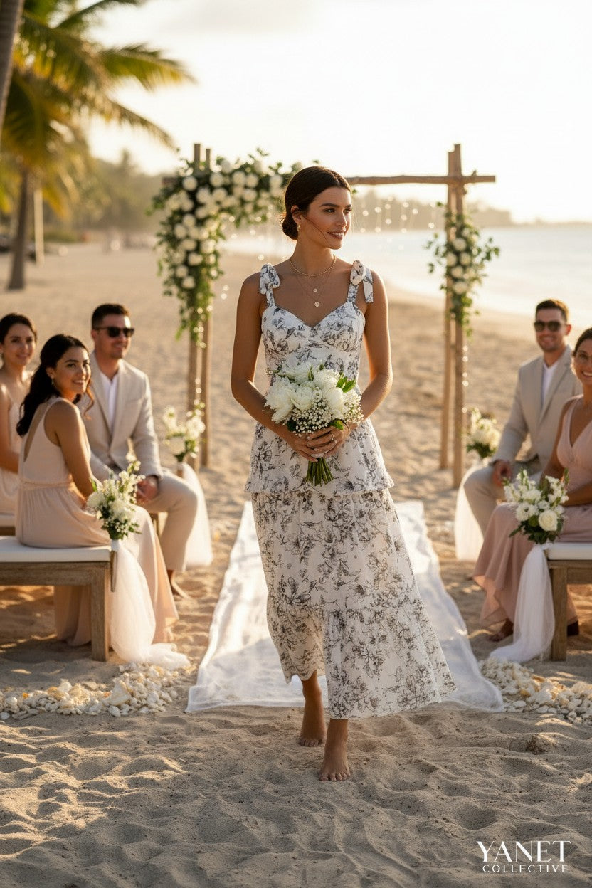 Yanet Collection Shop cream floral maxi dress with ruffled layers, sweetheart neckline, and spaghetti straps on a beach