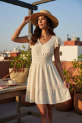 Yanet Collection Shop cream short dress with flutter sleeves, v-neckline, and tiered skirt worn by a woman in a hat.