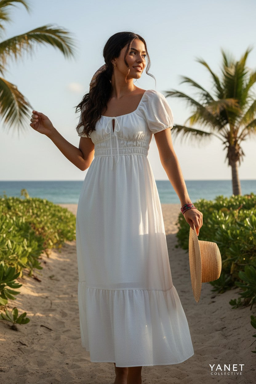 Yanet Collection Shop ivory maxi dress with puff sleeves, smocked bodice, and ruffled hem on a sunny beach