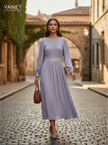 Yanet Collection Shop lavender long sleeve maxi dress with a pleated bodice and flowing skirt worn on a cobblestone street