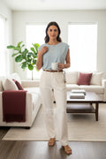 Yanet Collection Shop light blue short sleeve blouse with a gathered neckline worn with cream trousers in a living room