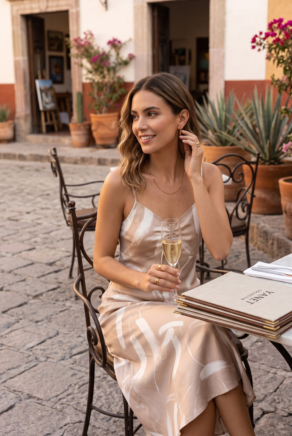 Yanet Collection Shop peach spaghetti strap maxi dress with a white brushstroke pattern worn by a woman at a cafe