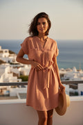 Yanet Collection Shop peach short sleeve tunic dress with a belted waist worn by a woman on a sunny balcony