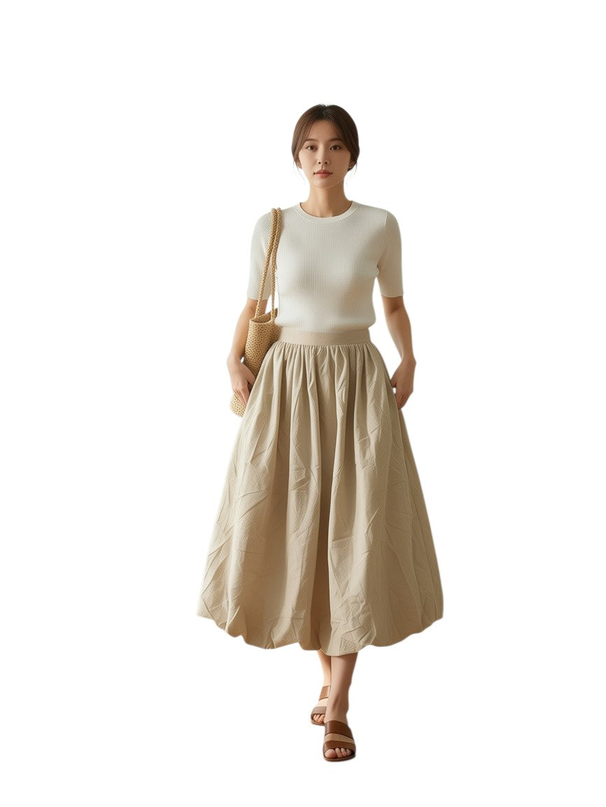 Woman wearing a Yanet Collection Shop white ribbed knit top and beige midi skirt with a woven shoulder bag
