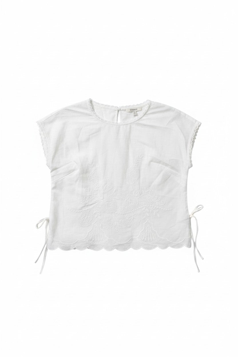 Yanet Collection Shop white short sleeve top with floral embroidery, side ties, and a scalloped hem.