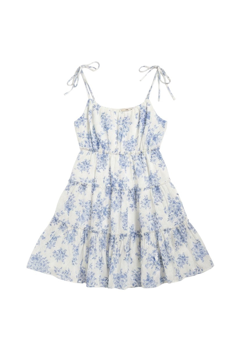 Yanet Collection Shop white mini dress with blue floral print, tiered skirt, and adjustable spaghetti tie straps.