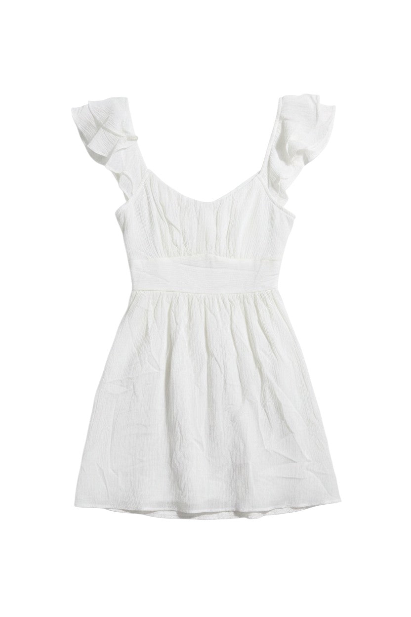 Yanet Collection Shop white mini dress with flutter sleeves, fitted waistband, and textured fabric for summer.