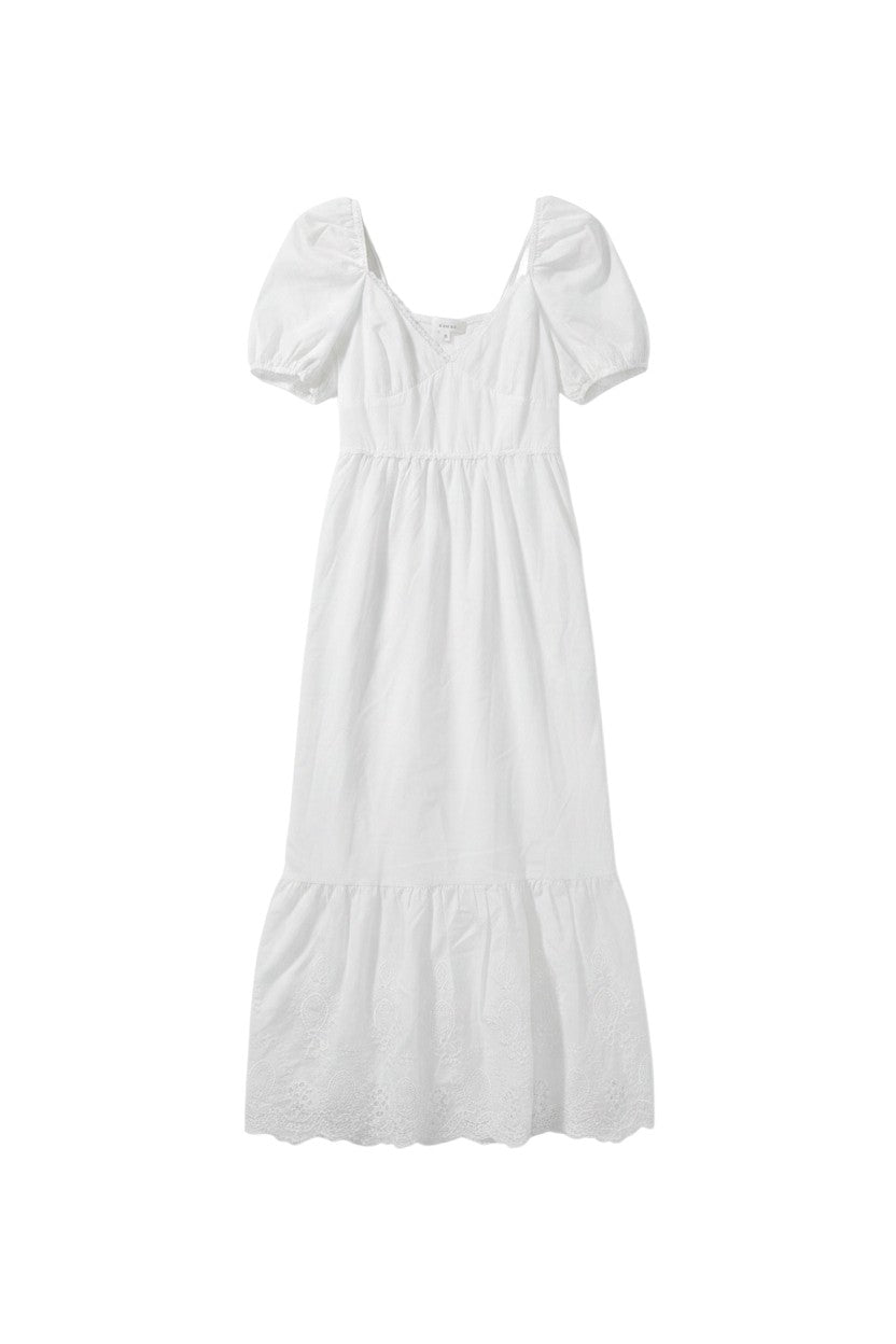 Yanet Collection Shop white maxi dress with puff sleeves, v-neckline, and delicate lace trim hem in a flowing style.
