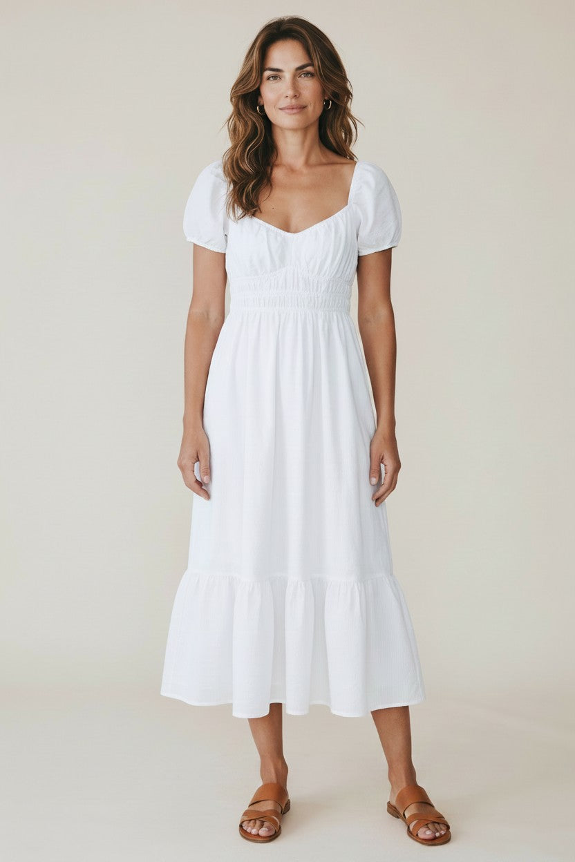 Model wearing a Yanet Collection Shop white maxi dress with short puff sleeves, smocked bodice, and ruffled hem